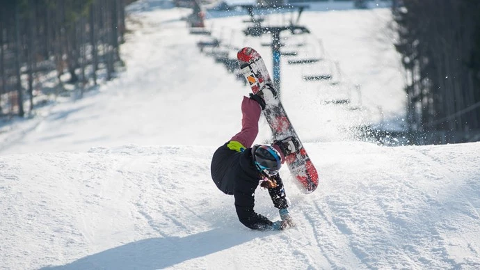 滑雪板持有他們的手，同時落在滑雪坡上